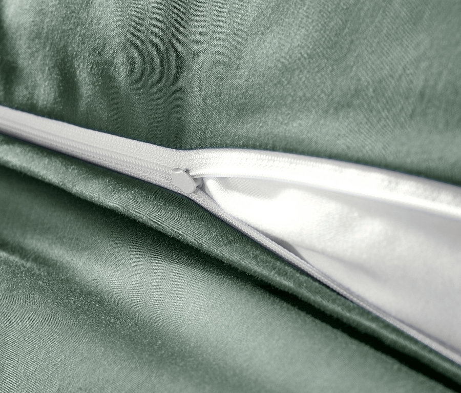 Detail zelenej posteľnej bielizne z bavlneného saténu so zipsom.