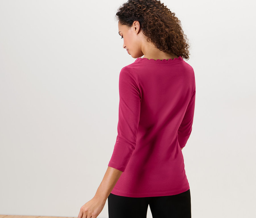 Žena má na sebe malinovo červené tričko s trojštvrťovým rukávom.