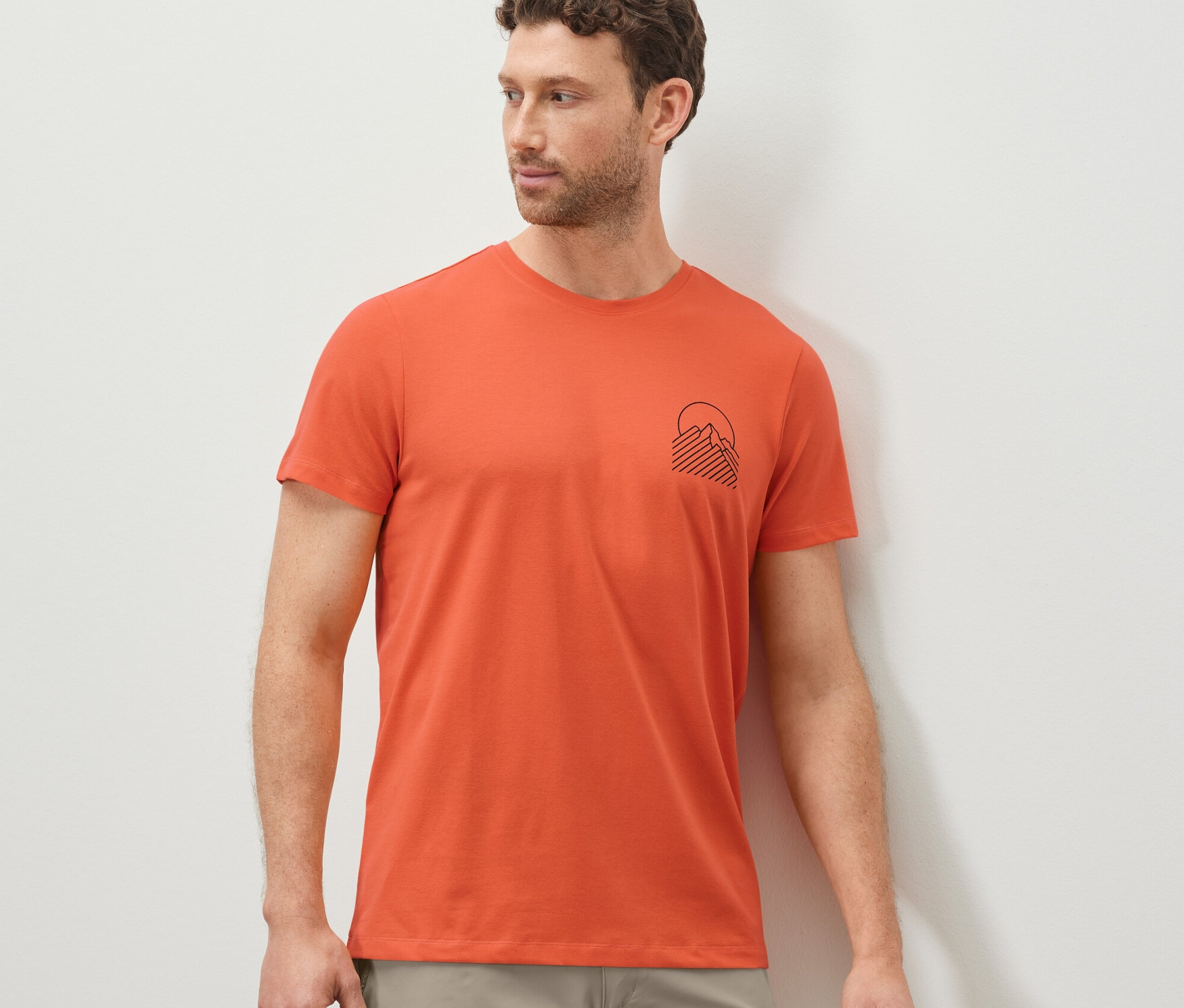 Muž má na sebe oranžové tričko s potlačou.