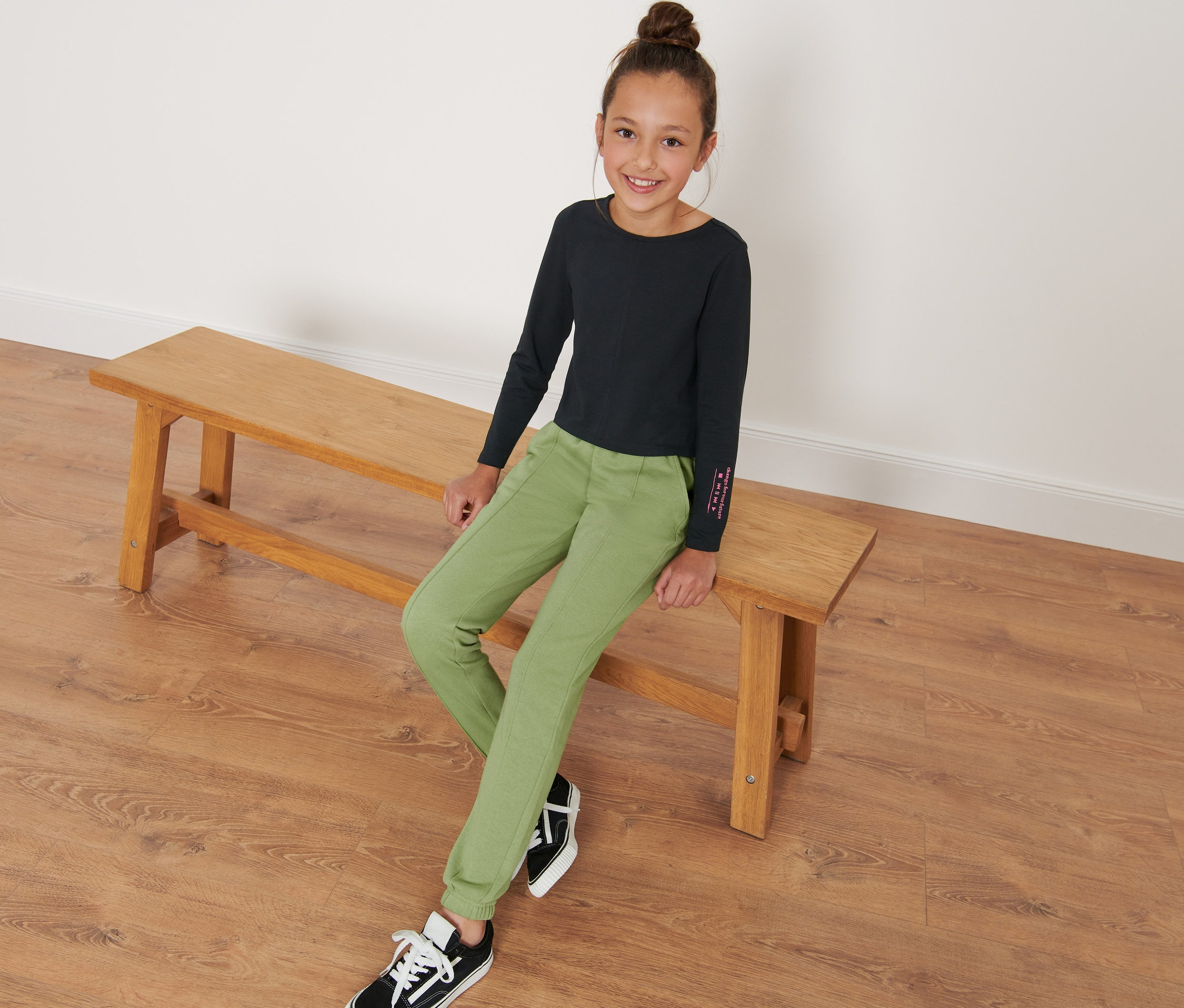 Dievča sedí na lavici a má na sebe detské tepláky.