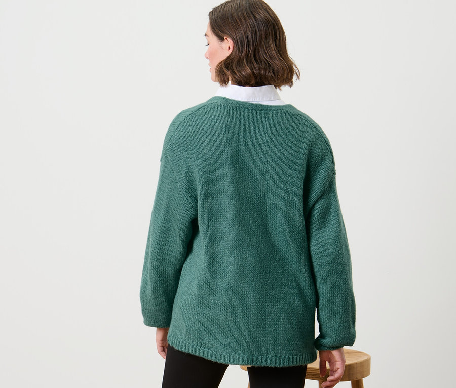 Žena má na sebe otvorený kardigán z hrubej pleteniny.