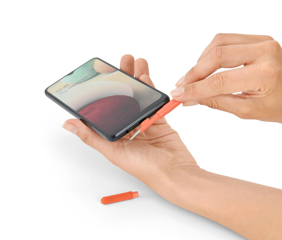 Žena čistí telefón súpravou na čistenie na písací stôl 4 v 1.