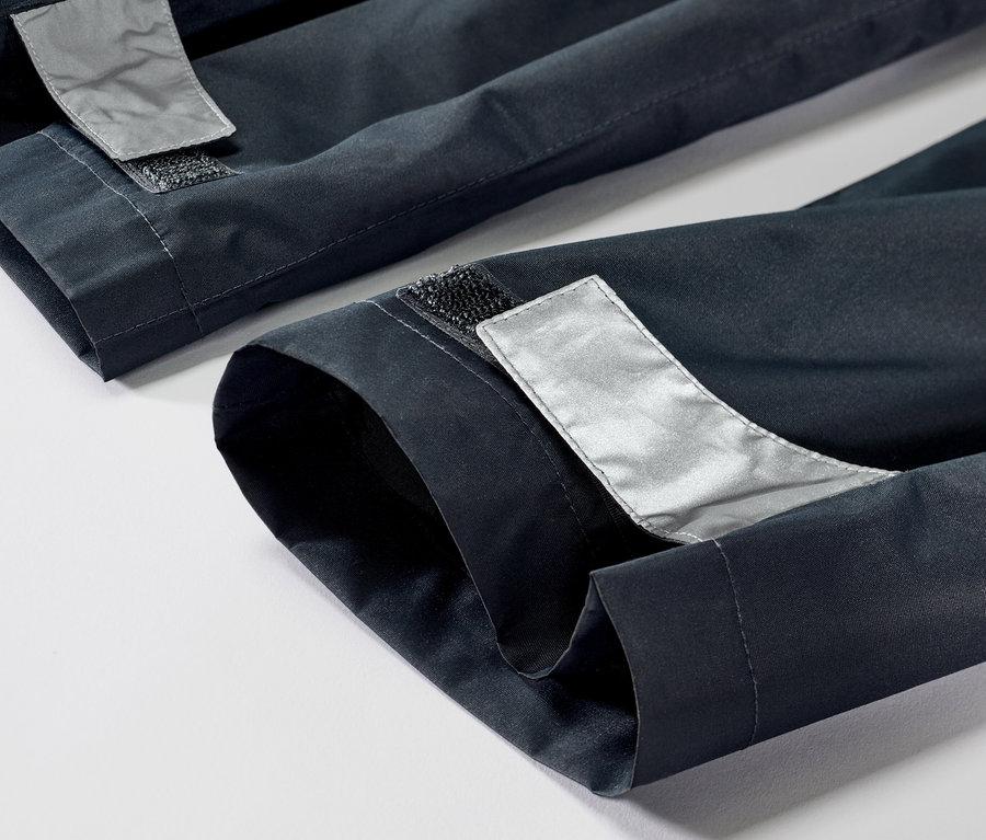 Detail detských nohavíc do dažďa s reflexnými prvkami a suchým zipsom na leme.