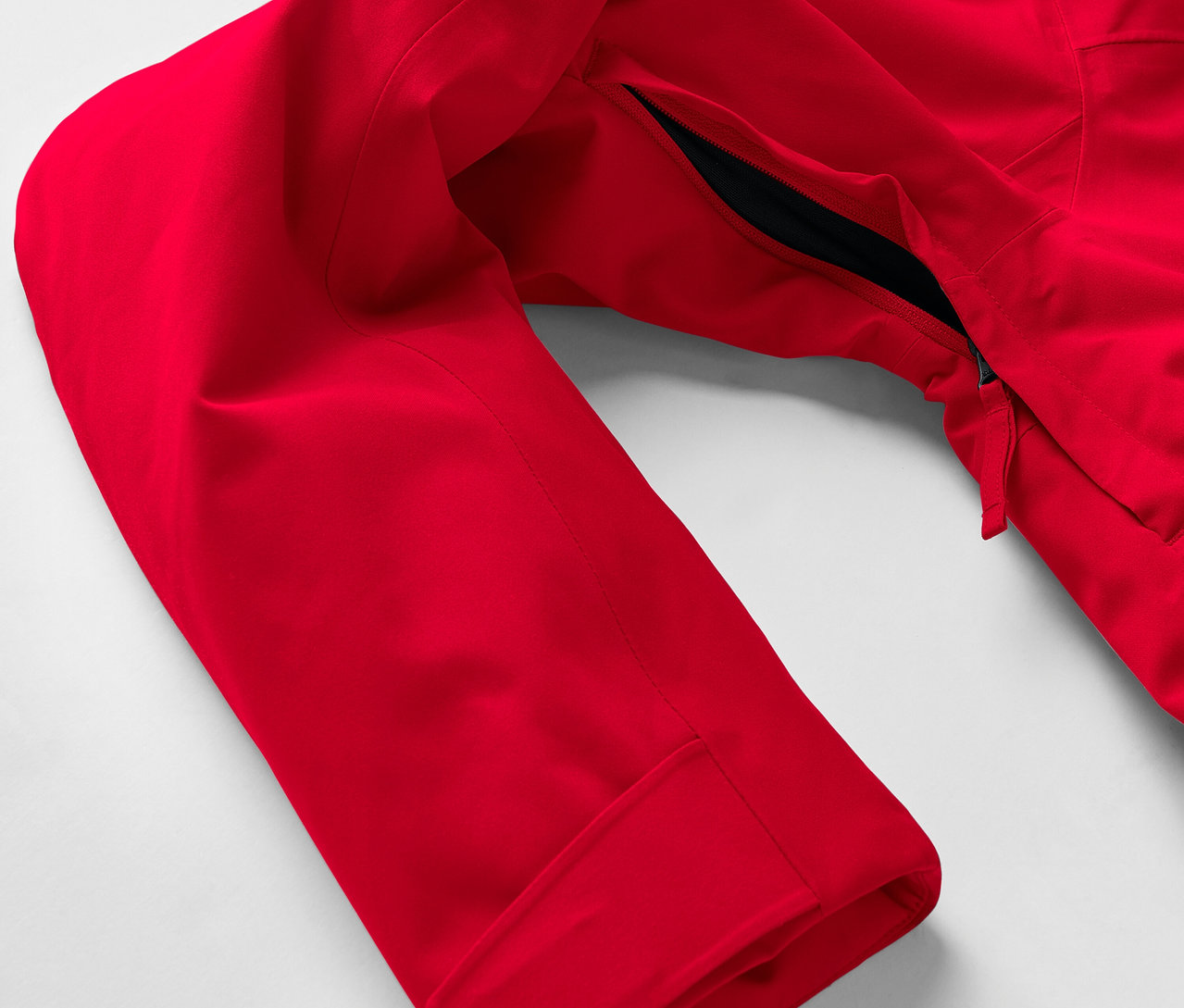 Detail červenej bundy s rukávom a vreckom na zips.