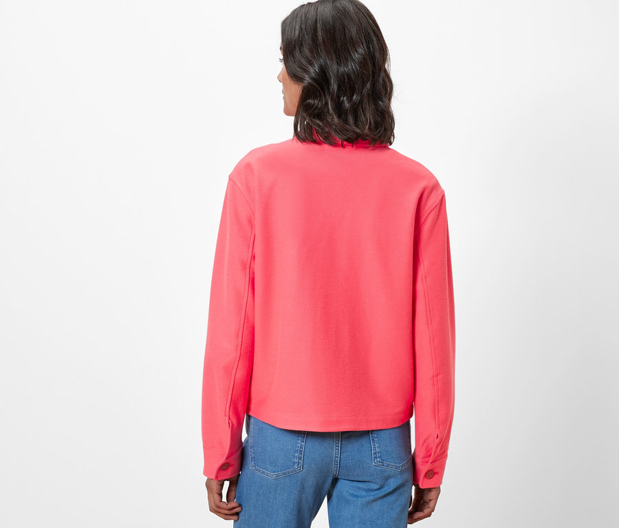 Pohľad zozadu na ženu v džersejovej bunde a džínsoch.