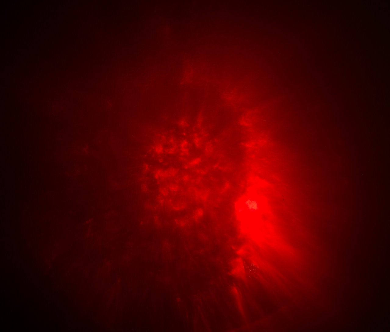 Abstraktný obraz s červenými škvrnami a svetelnými efektmi.