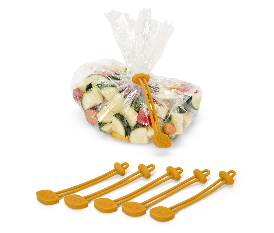 Kocky cukety, mrkvy a papriky v plastovom vrecku, uzavretom žltou silikónovou sťahovacou páskou s motívom listu. Pod vreckom sú štyri žlté silikónové pásky.