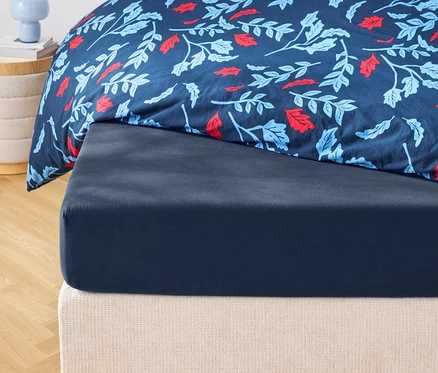 Detail tmavomodrej plachty a vzorovanej prikrývky s kvetinovým motívom.