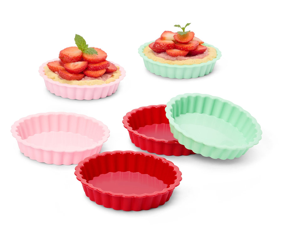 Niekoľko farebných formičiek na tartaletky, niektoré plnené jahodovými tartaletkami.