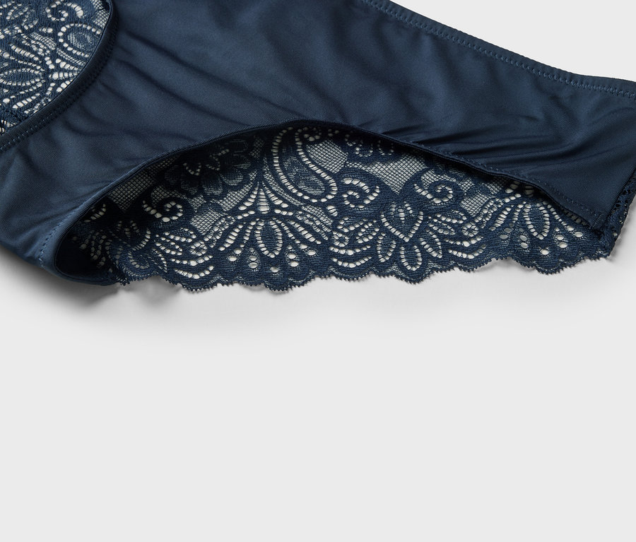 Detailný záber na tmavomodré dámske nohavičky s čipkovaným lemovaním.