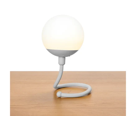 Sivá guľovitá lampa so zakriveným krkom stojí na drevenom stole.