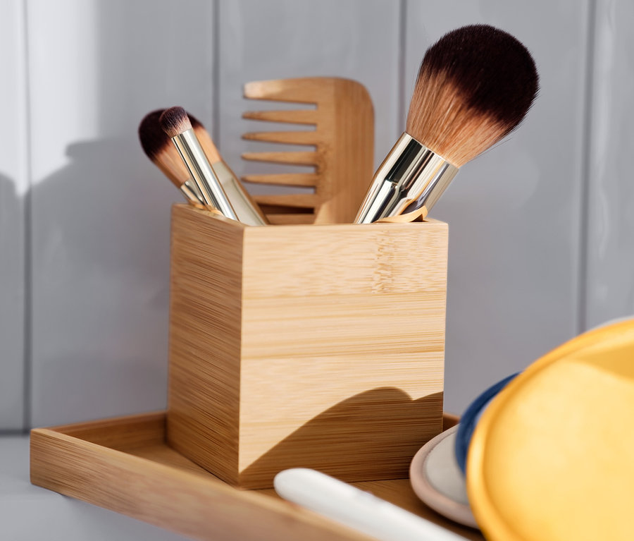 Na drevenom podnose sú odličovacie tampóny modrej, žltej a hnedej farby a organizér so štetcami na make-up a hrebeňom.