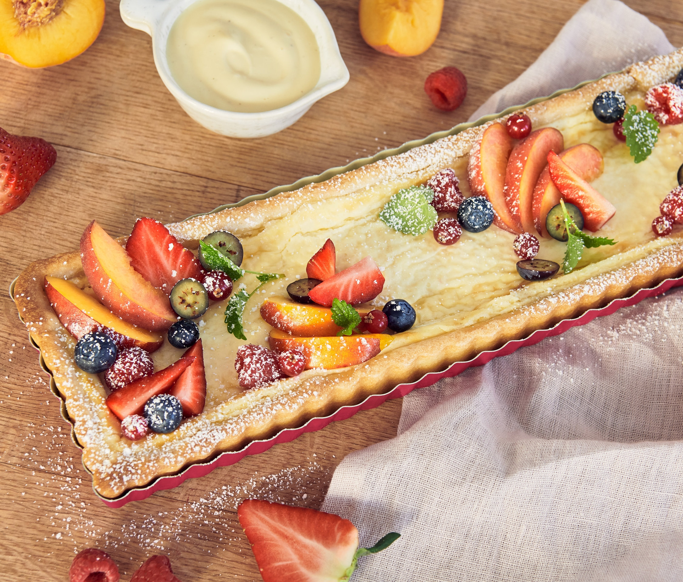 Ovocný koláč vo forme na tarte s broskyňami, jahodami, malinami a čučoriedkami.