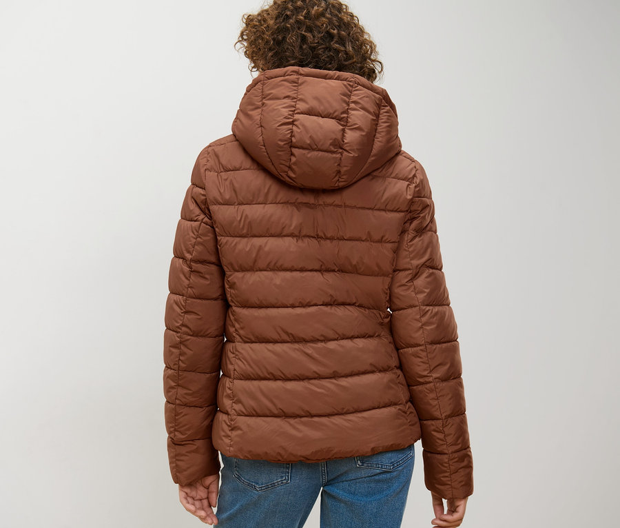 Žena zozadu má na sebe koňakovú prešívanú bundu s kapucňou.