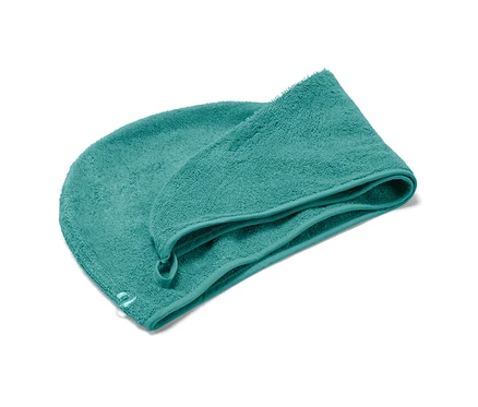 Akvamarínový uterákový turban leží na bielom pozadí.