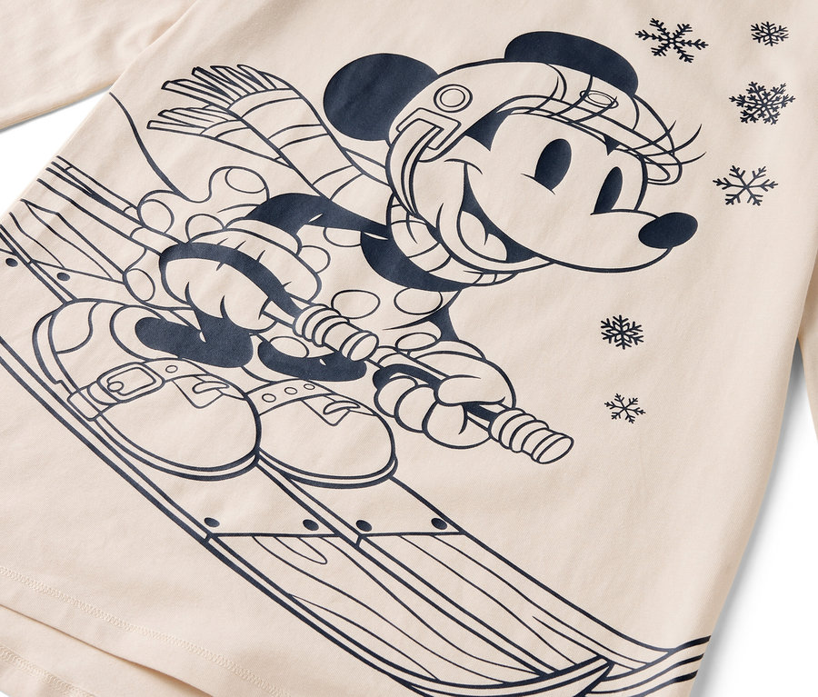 Kreslená postavička myšky Minnie na lyžiach s helmou, šálom a rukavicami na béžovom pozadí.