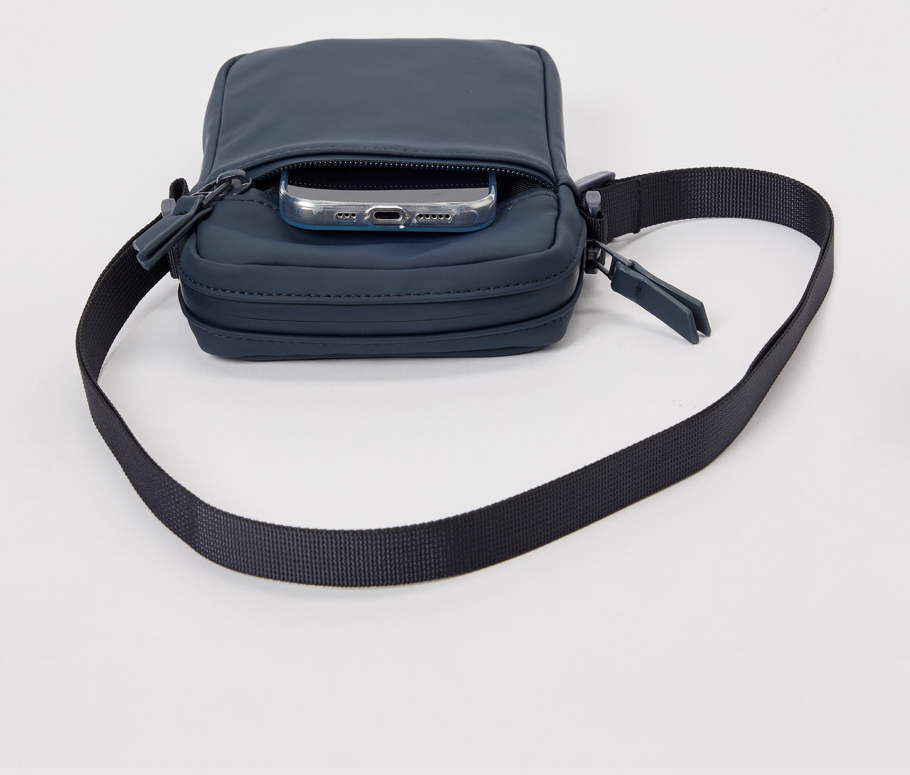 Modrá taška na rameno do dažďa s telefónom vo vrecku.