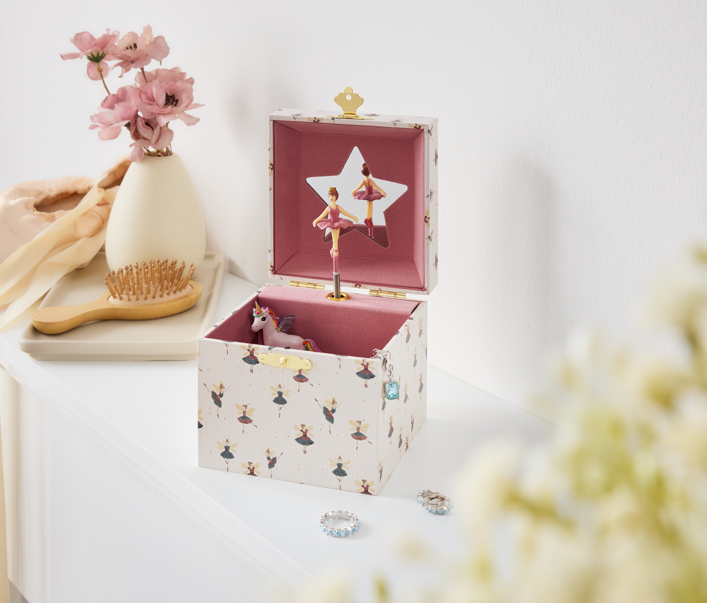 Otvorená hudobná skrinka s baletkami a jednorožcom na bielom stole.