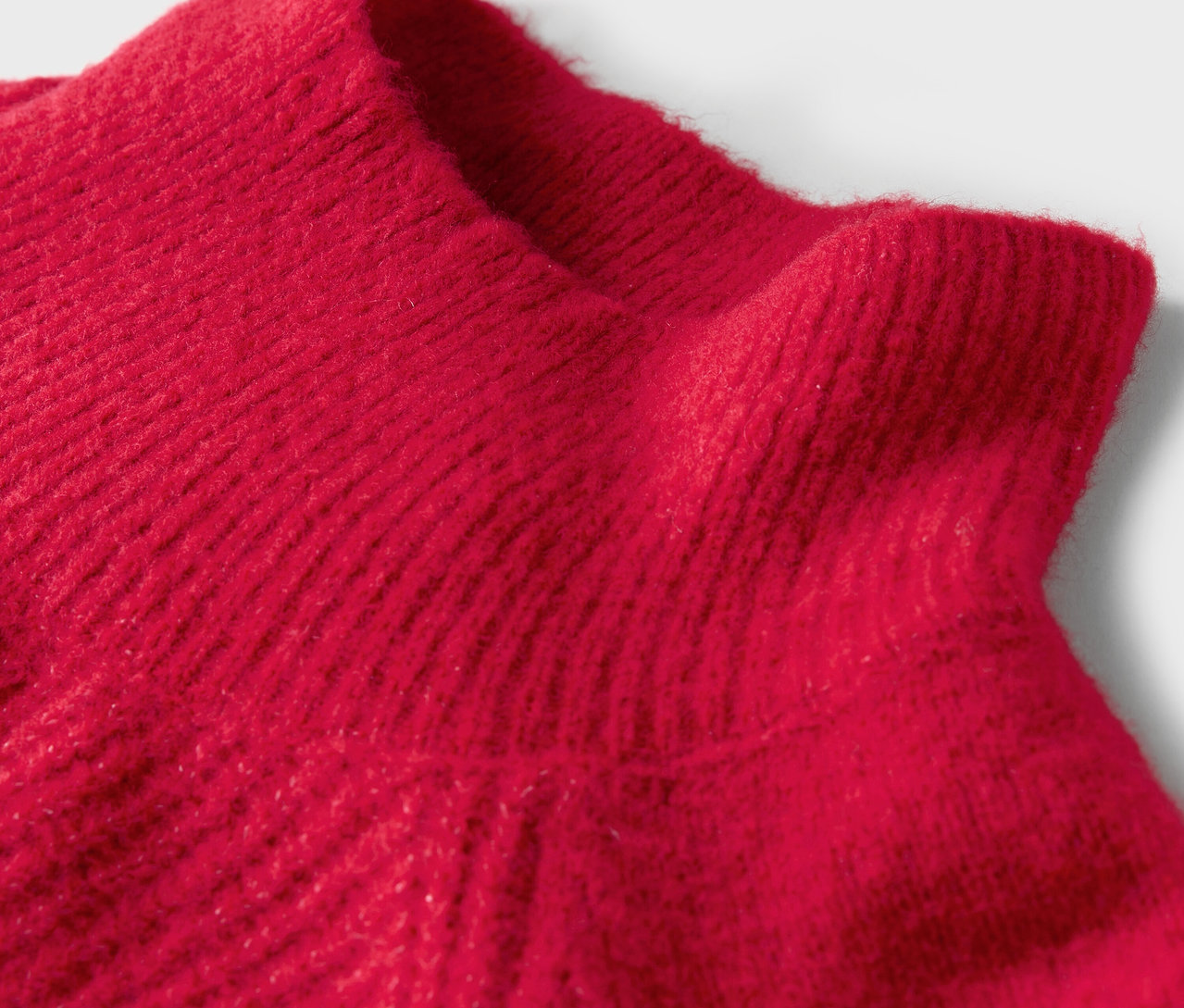 Detail červeného rolákového svetra.
