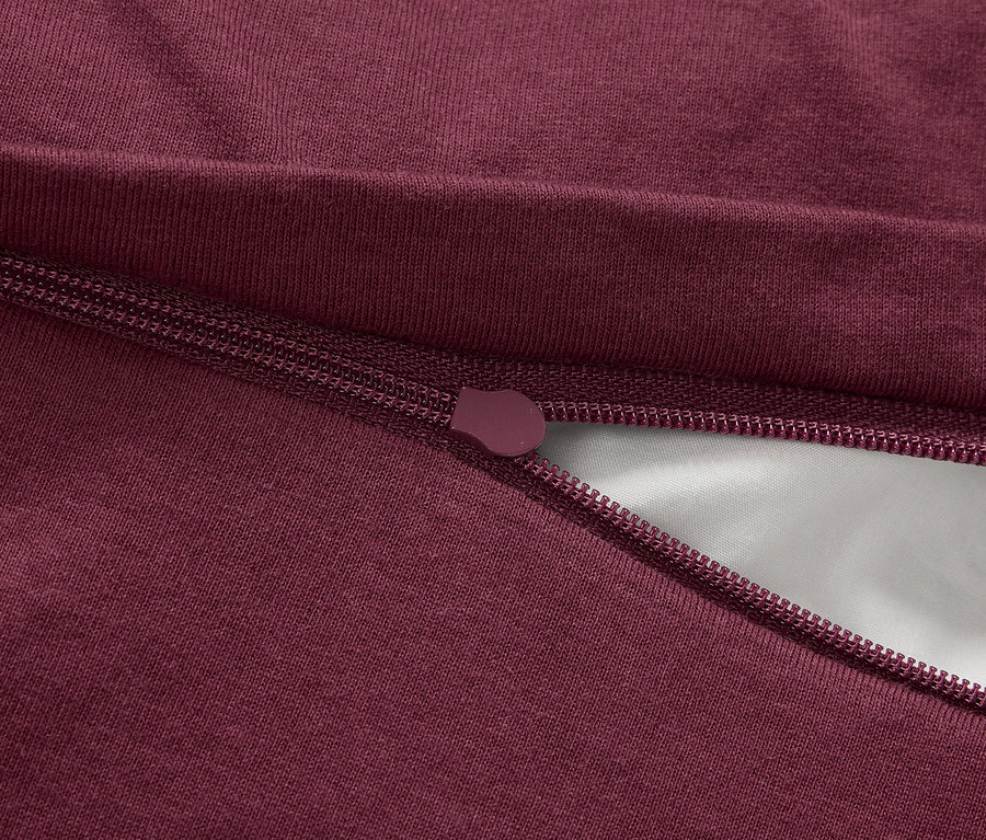 Detail bordového zipsu na látke.