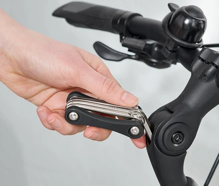 Ruka používa multifunkčný nástroj na riadidlách bicykla.