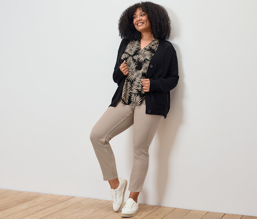 Žena pózuje v 7/8 tregínach, tope a svetri.