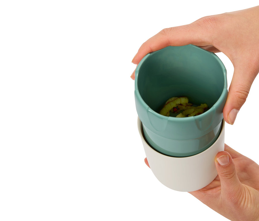 Ruky držia dva poháre, horný je tyrkysový s obsahom, spodný biely.