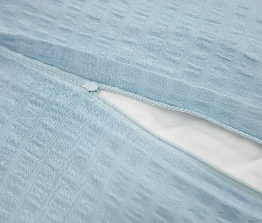 Detail svetlomodrej obliečky na vankúš so zipsom a bielou vnútornou vrstvou.