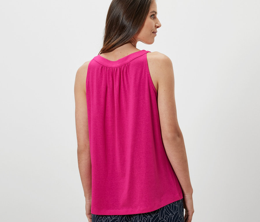 Žena sa pozerá cez rameno a má na sebe ružový top.