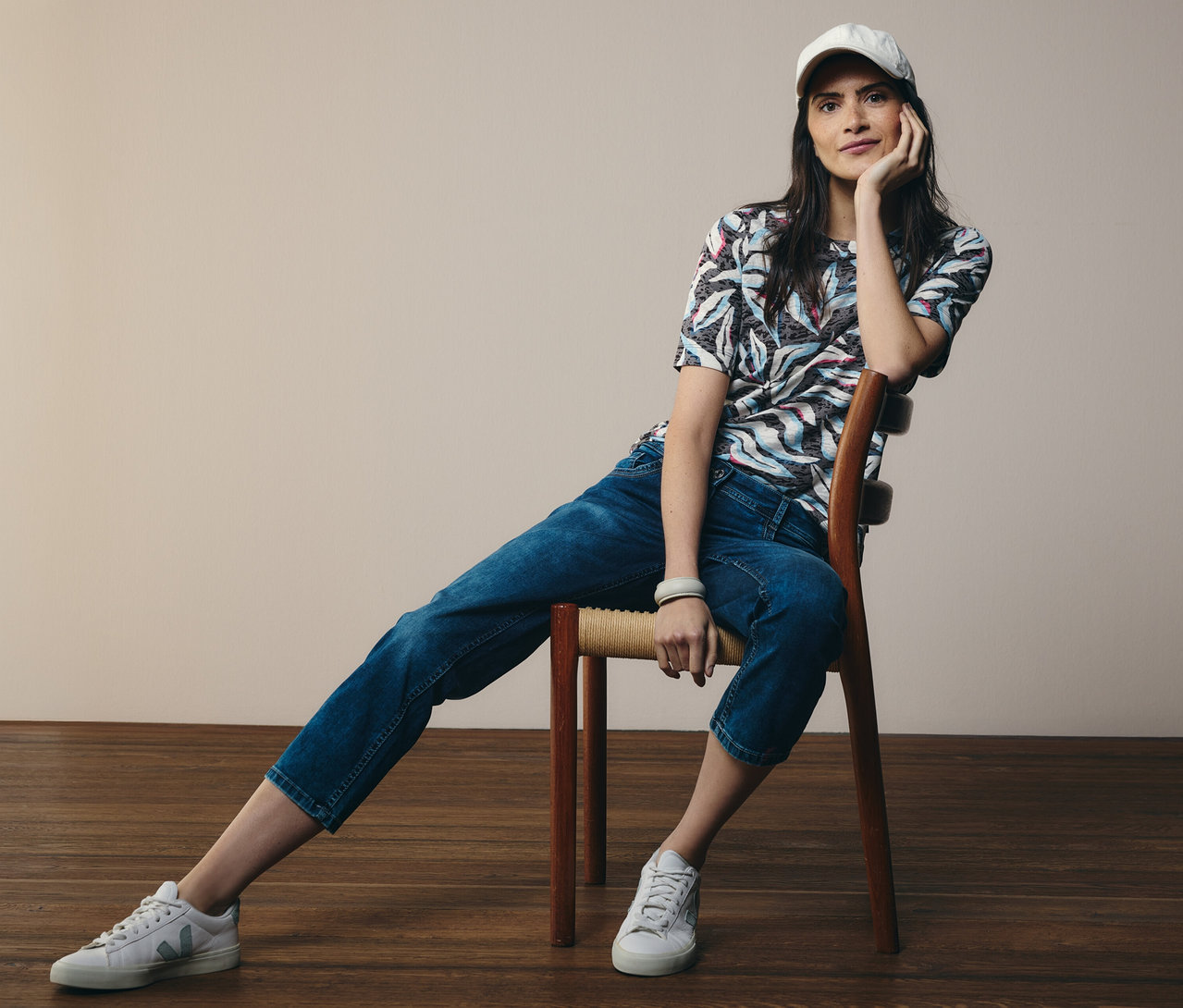 Žena sedí na stoličke, má na sebe modré tričko s krátkym rukávom CECIL a džínsy CECIL »Scarlett«.