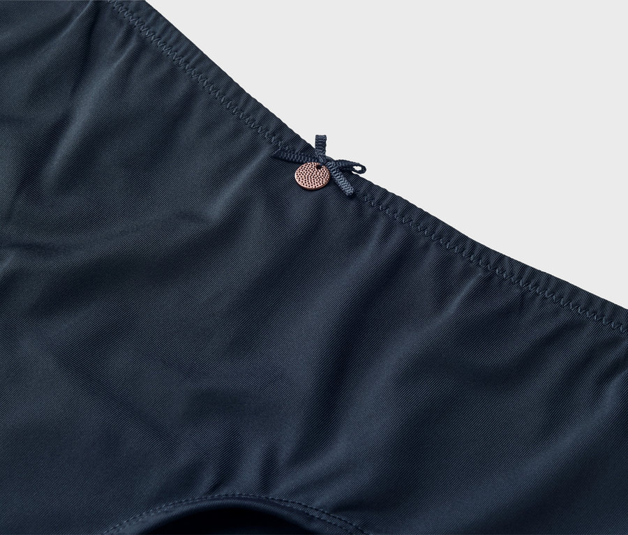 Detailný záber na tmavomodrú spodnú bielizeň s mašličkou a malým gombíkom.