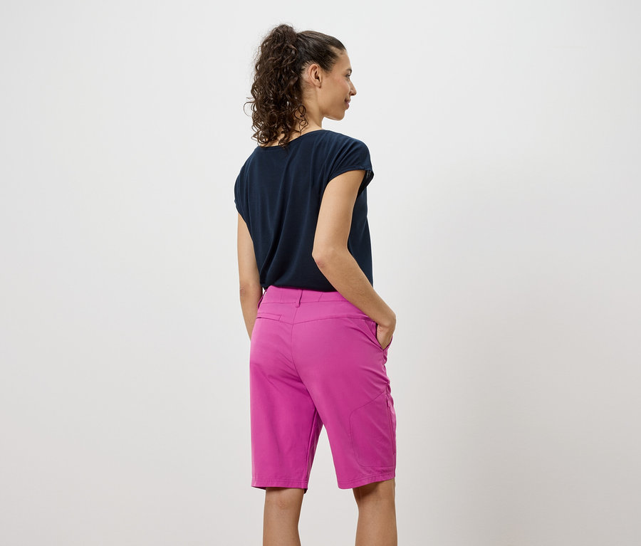 Pohľad zozadu na ženu v tmavom tričku a ružových šortkách.