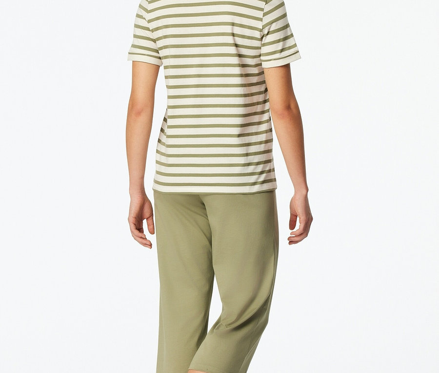 Žena zozadu v pruhovanom tope a zelených nohaviciach.