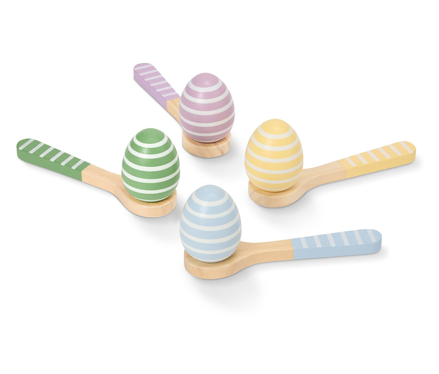 Štyri maľované, prúžkované kraslice v pastelových farbách ležia na malých drevených lyžičkách.