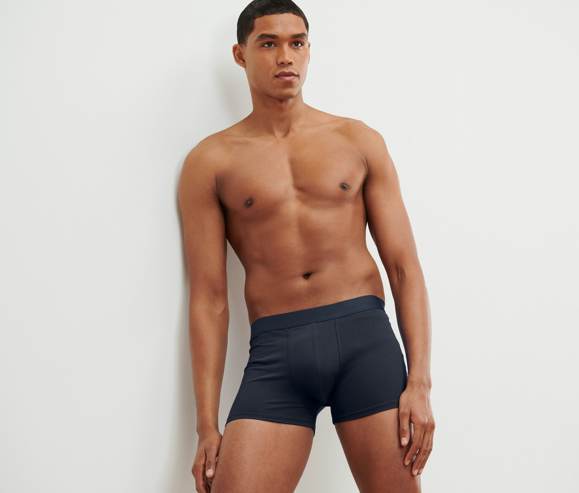 Muž opretý o stenu má na sebe boxerky, 4 ks.