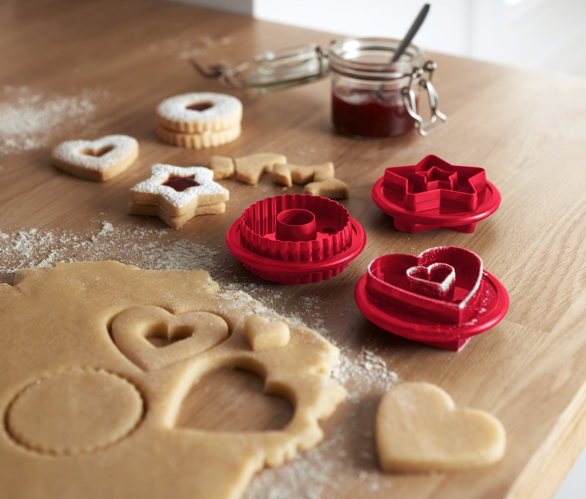 Na drevenom stole ležia linecké pečivo a vykrajovačky na linecké pečivo, 3 ks.