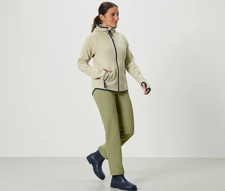 Žena kráča a má na sebe khaki softshellové nohavice.