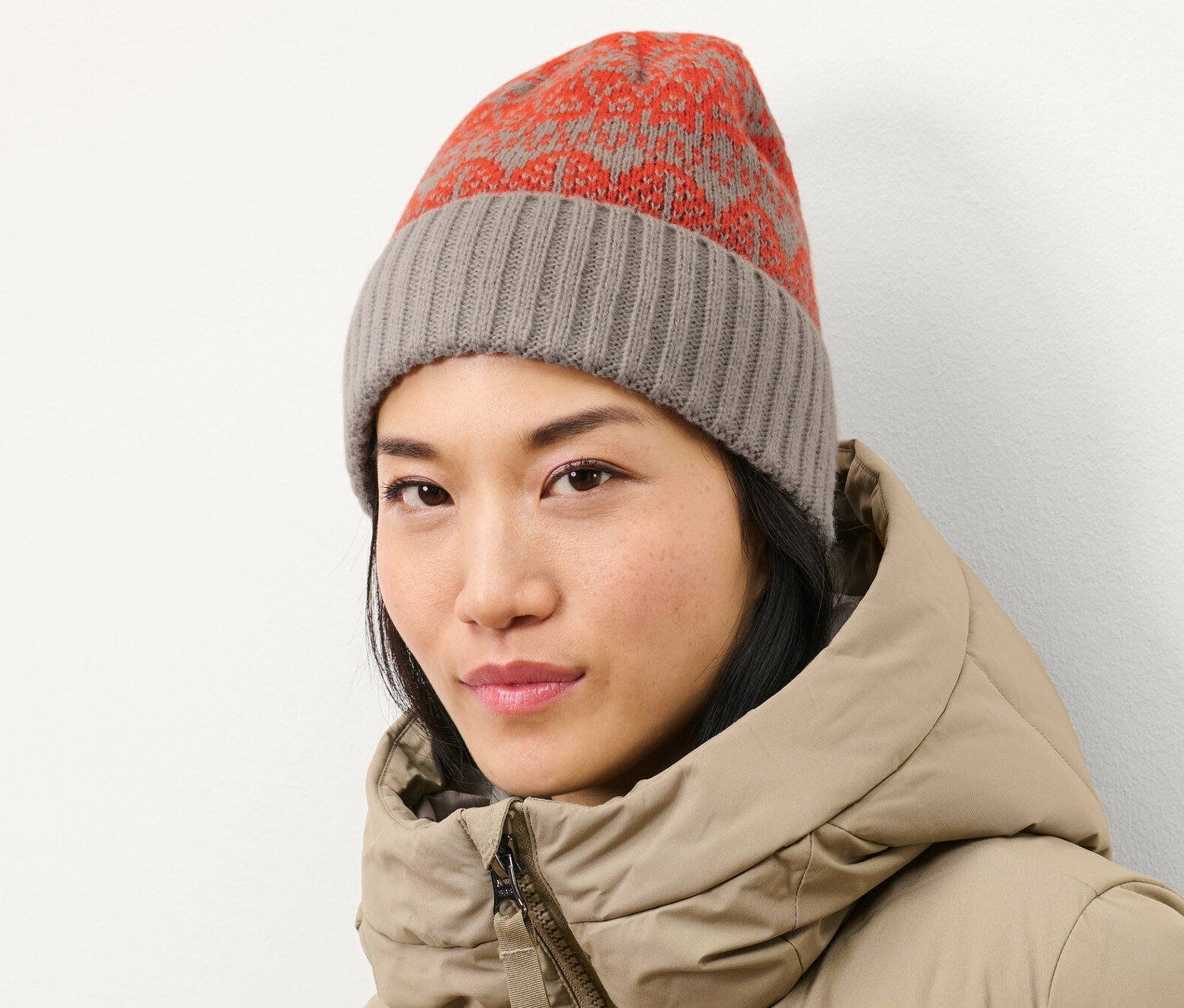 Žena má na sebe pletenú čiapku a páperovú bundu.