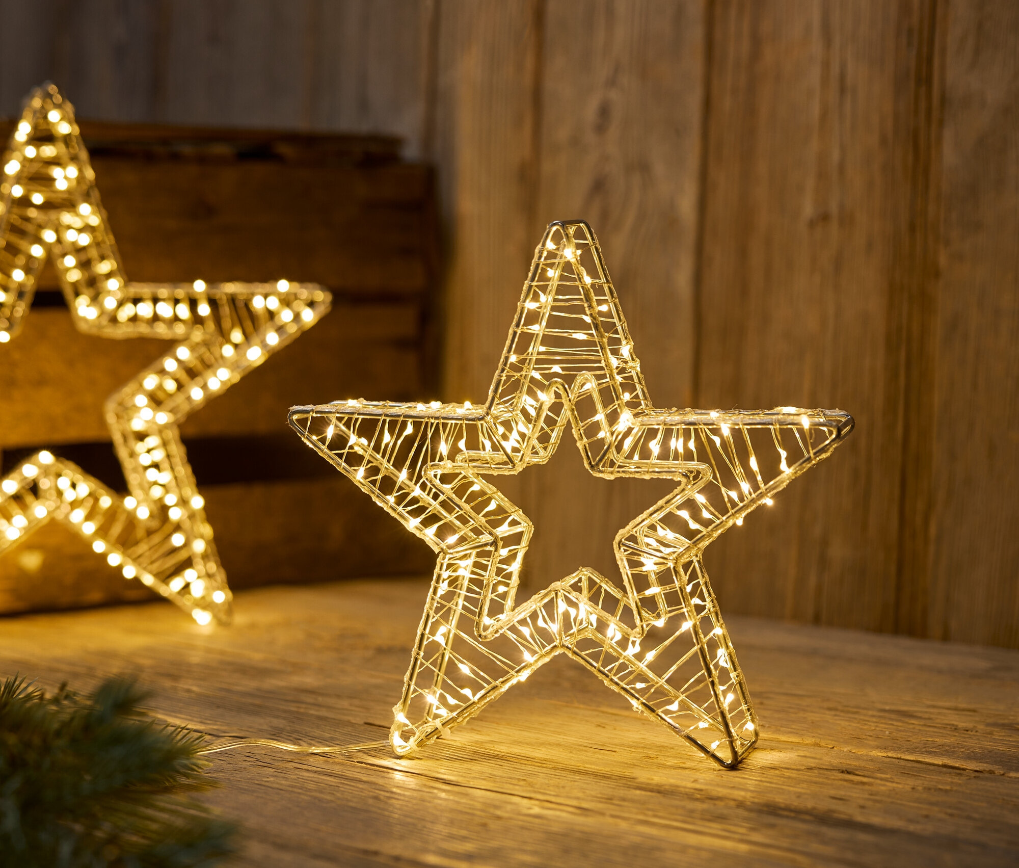 Osvetlené drôtené hviezdy na drevenom povrchu.