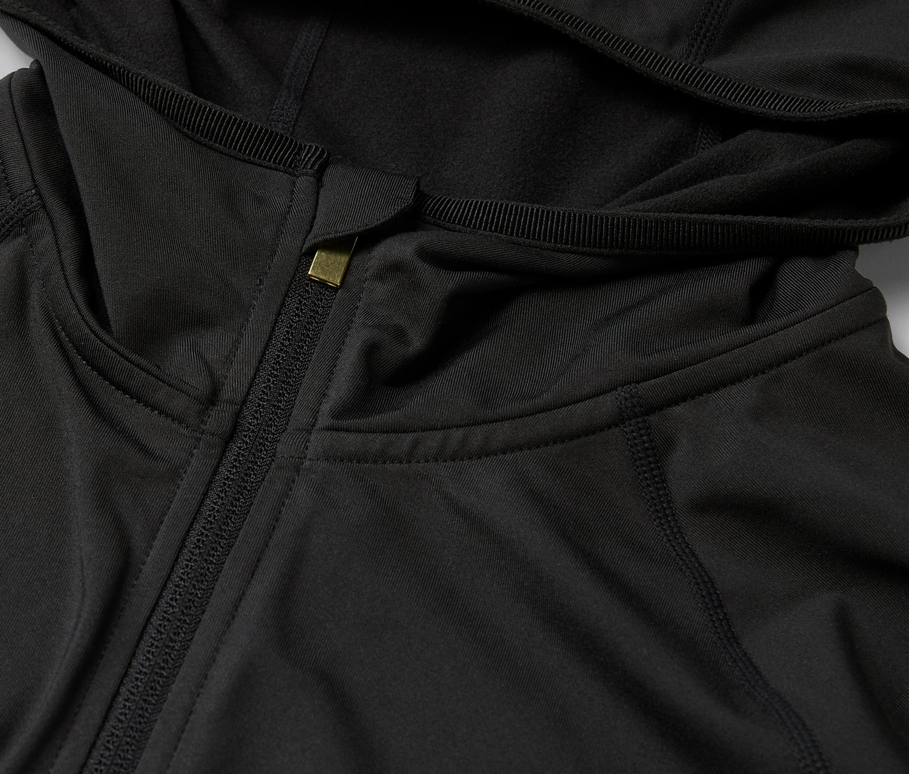 Detail čiernej mikiny s kapucňou a zipsom.