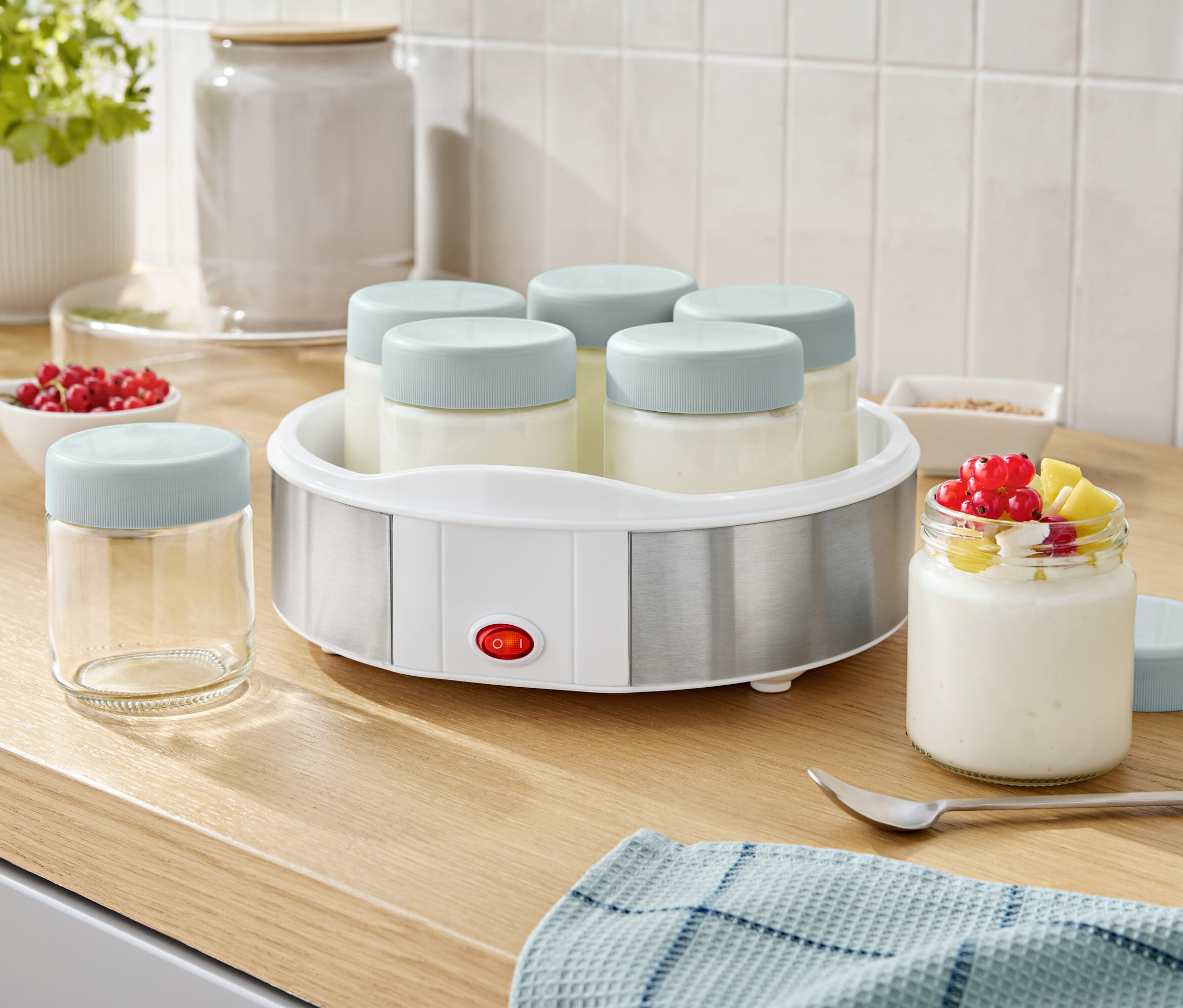 Jogurtovač so šiestimi pohármi a jedným pohárom jogurtu s ovocím.
