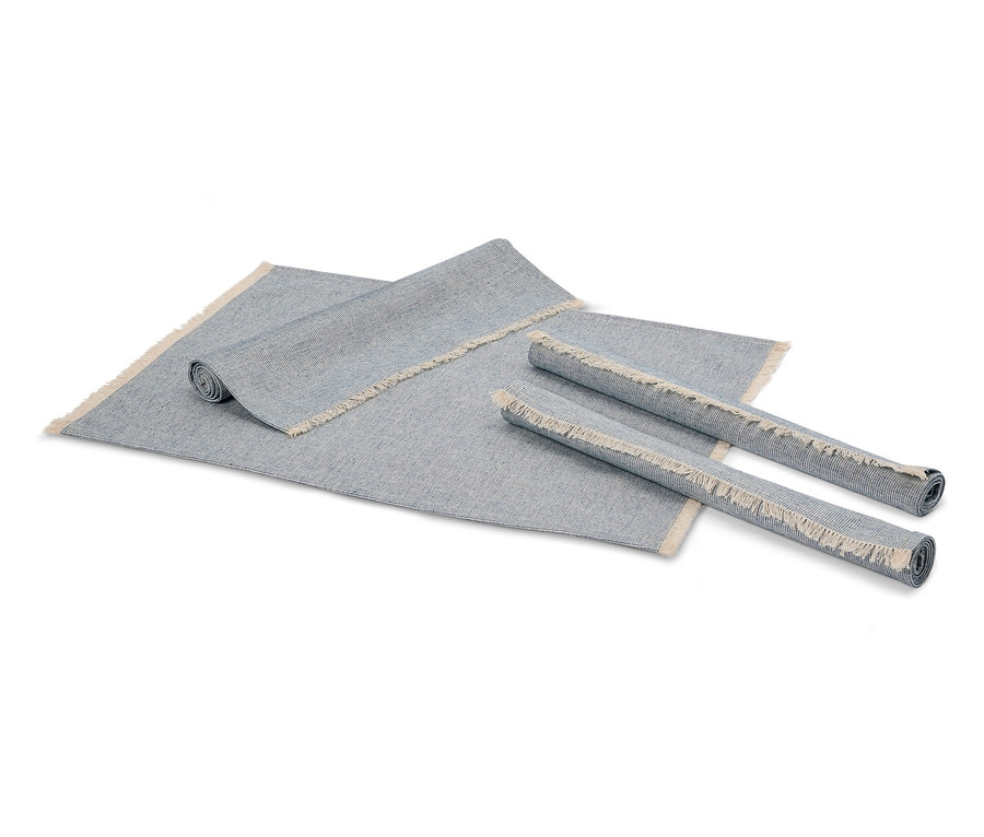 Dva zrolované sivé koberce a jeden rozložený sivý koberec so strapcami.