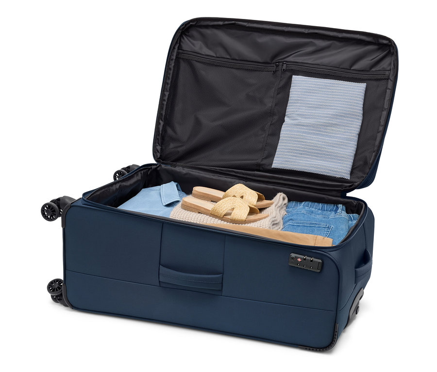 Otvorený textilný kufor, veľký, s oblečením a sandálmi vnútri.