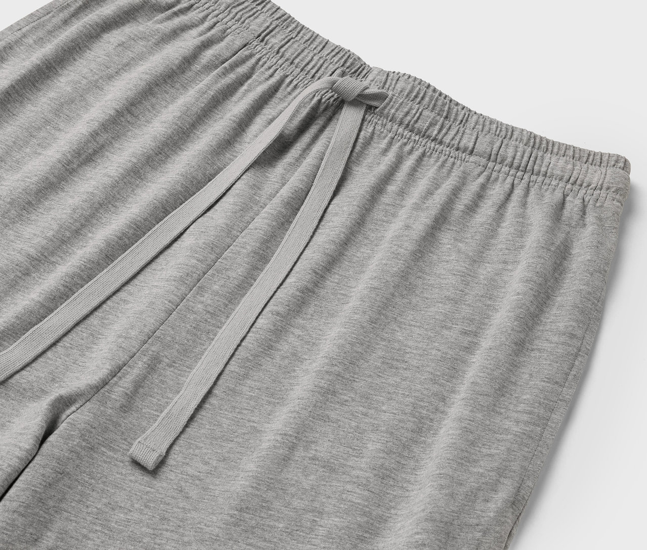 Detail sivých teplákov s elastickým pásom a šnúrkou.