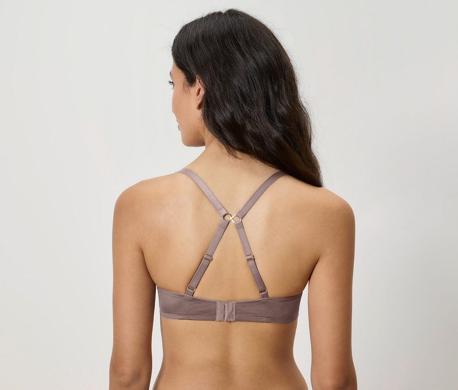 Pohľad zozadu na ženu s hnedými vlasmi, ktorá má na sebe sivú podprsenku.