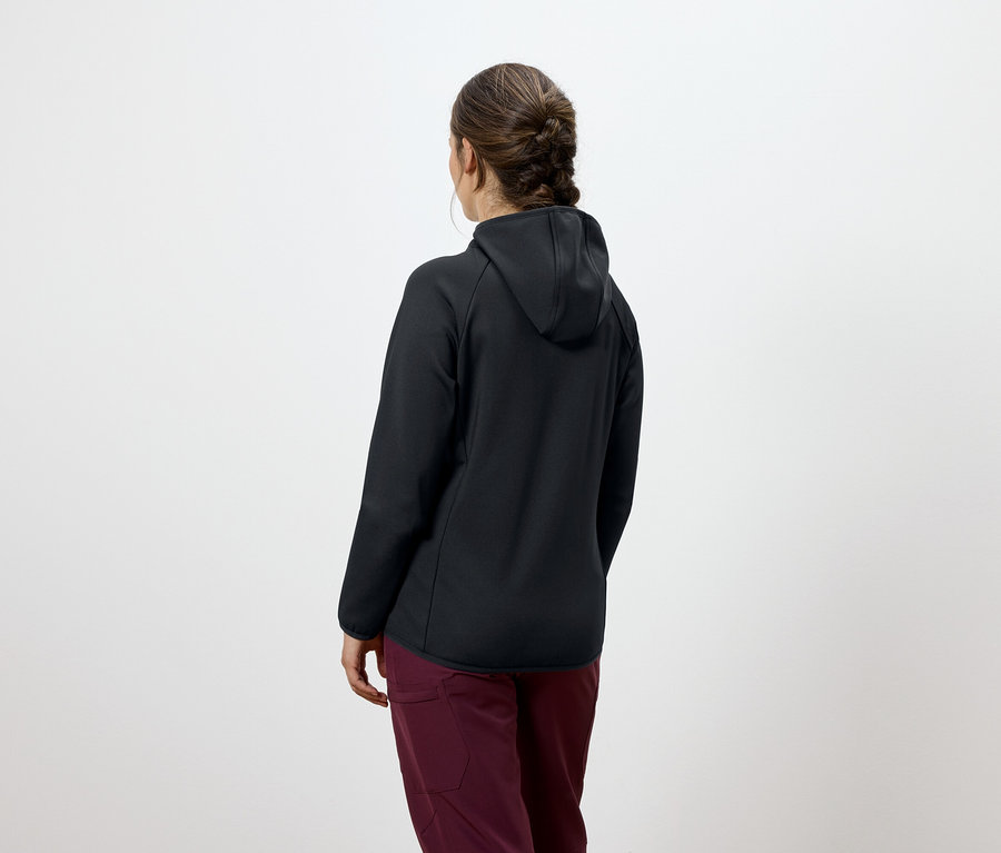 Pohľad zozadu na ženu s hnedými zapletenými vlasmi, oblečenú v čiernej mikine s kapucňou a bordových nohaviciach.