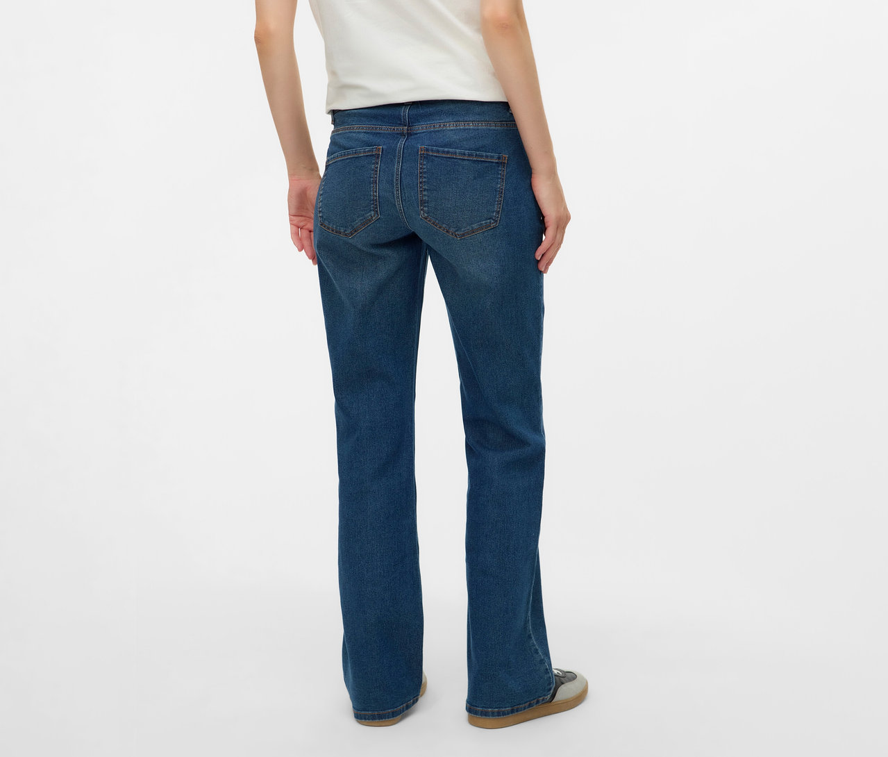 Pohľad zozadu na ženu v bielom tričku a rozšírených džínsoch MAMALICIOUS »MLEDINA« na bielom pozadí.