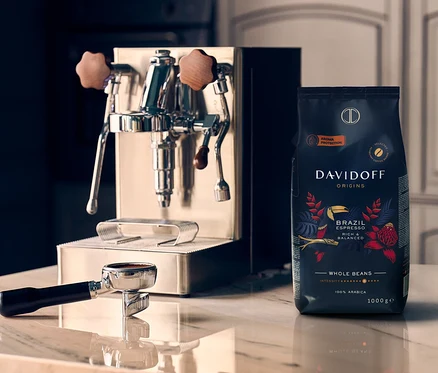 Na mramorovej doske stojí kávovar vedľa balenia zrnkovej kávy DAVIDOFF CAFÉ ORIGINS Brazil.