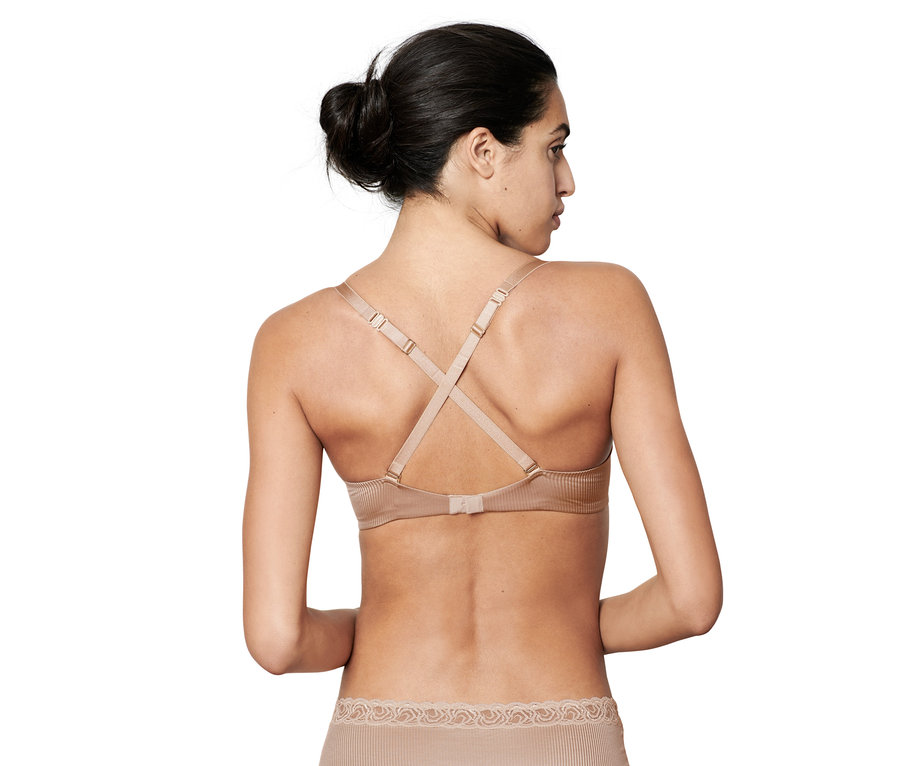 Žena chrbtom k fotoaparátu má na sebe béžovú variabilnú podprsenku push-up.