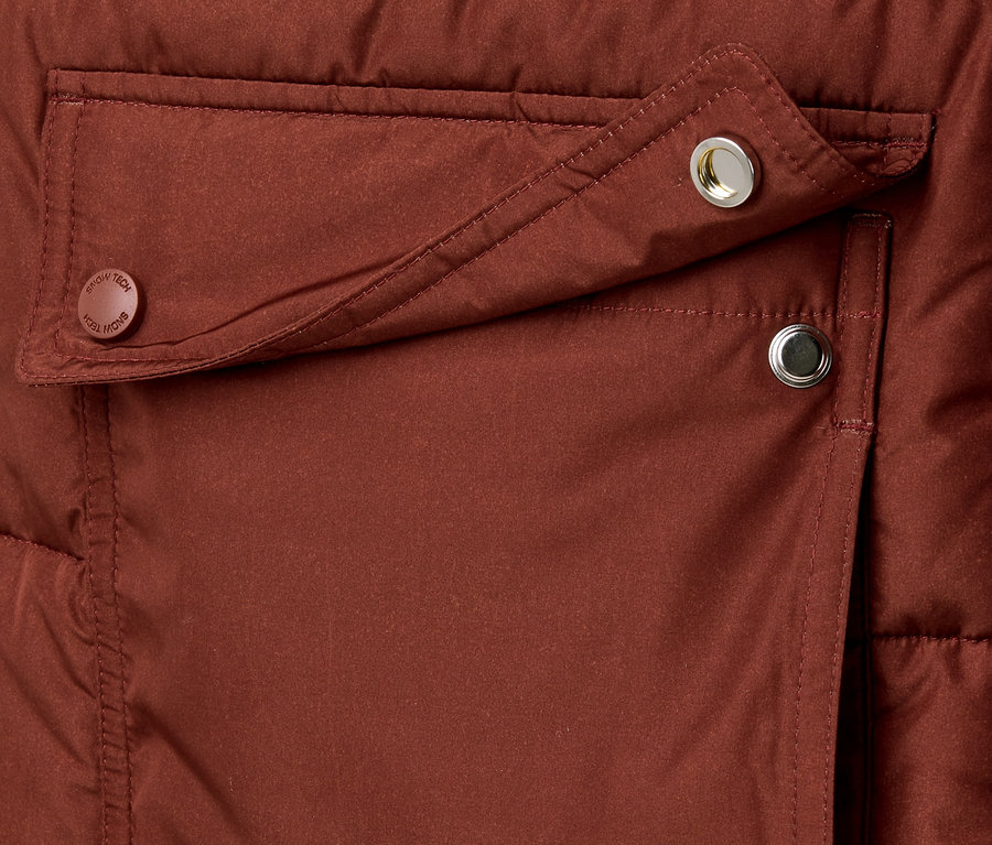 Detail prešívaného kabáta s vreckom a patentkami.